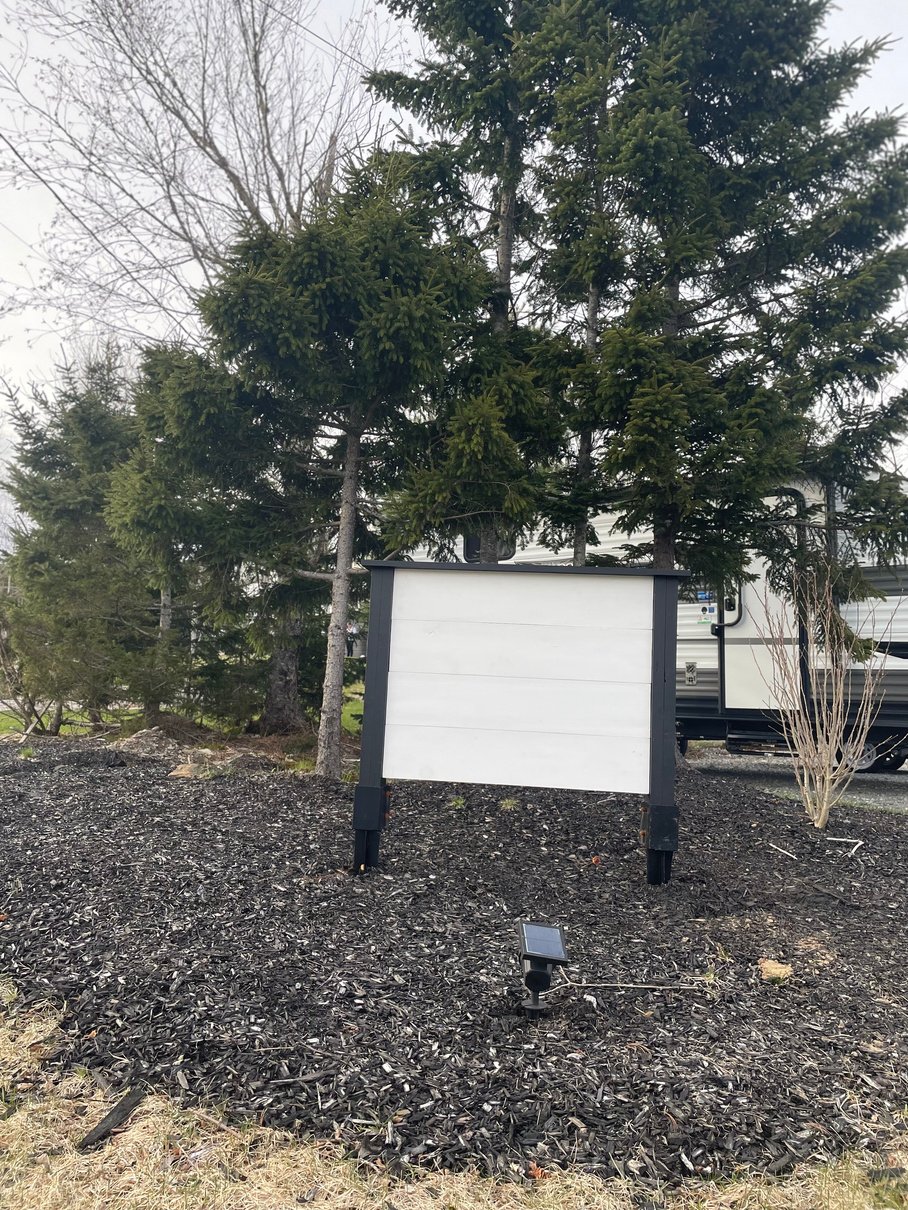 A white sign with black posts to put house number on at end of a driveway. 